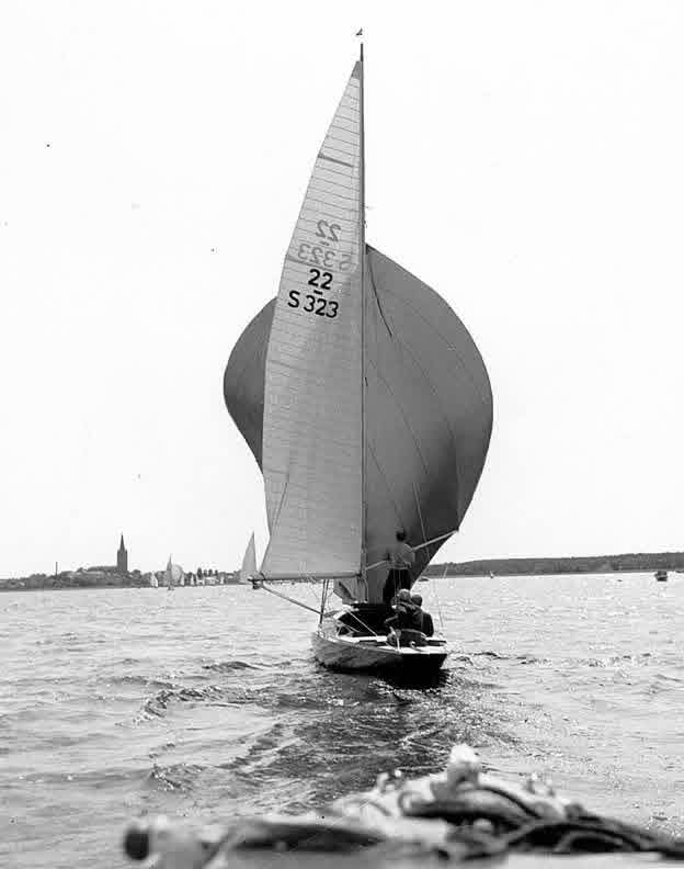 Segelbåt med spinnaker mot Mariestads siluett under Torsö Runt